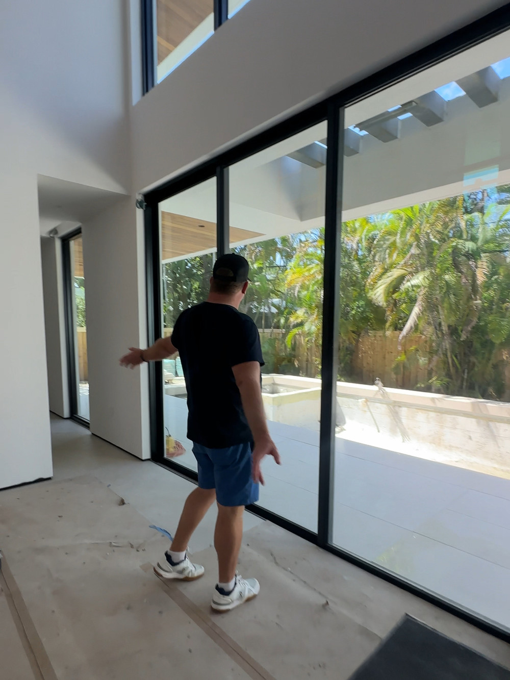 Double-height living space opening to the pool terrace through a full-height glass wall